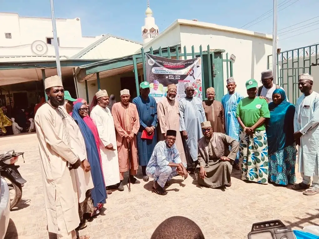 LHAAT members, community leaders and health workers stand together outside a health facility