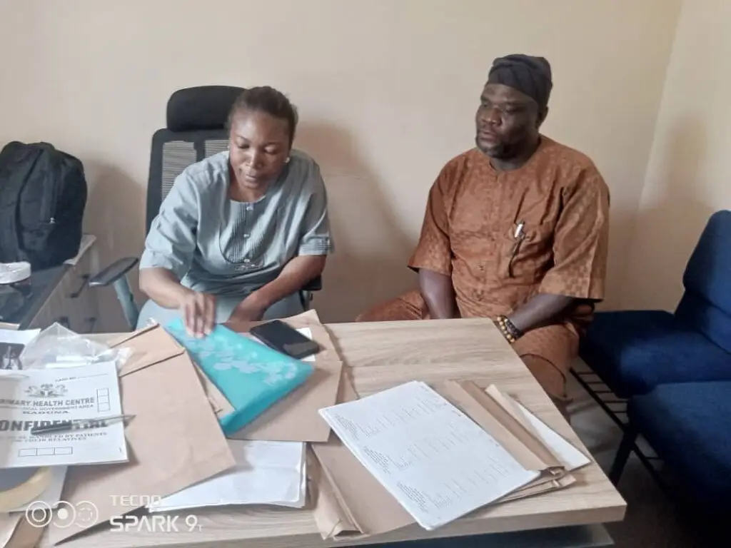 LHAAT members reviewing documents with a facility officer at a desk in Igabi, Kaduna