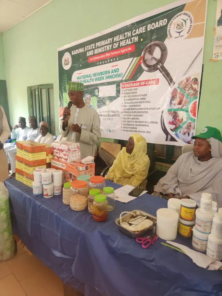 Officials and community members beside the campaign banner at the MNCH Week flag-off at PHC Yakasai in Soba, Kaduna