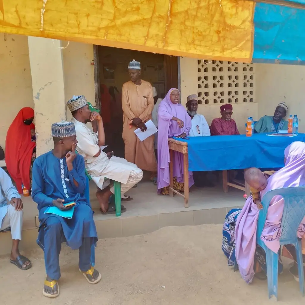 Community representatives seated outside at the Babban Dodo town hall meeting in Zaria, Kaduna
