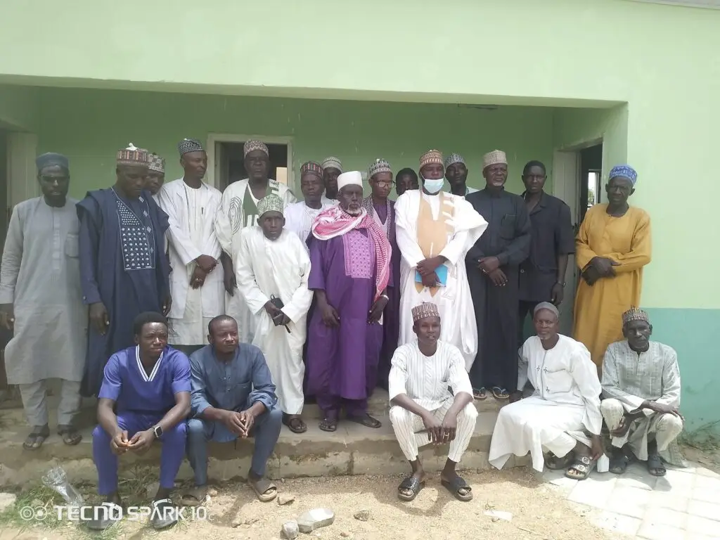 LHAAT committee members, health workers and community members posing together outside PHC Jajaye in Rogo, Kano