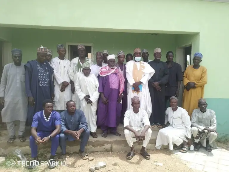 LHAAT committee members, health workers and community members posing together outside PHC Jajaye in Rogo, Kano