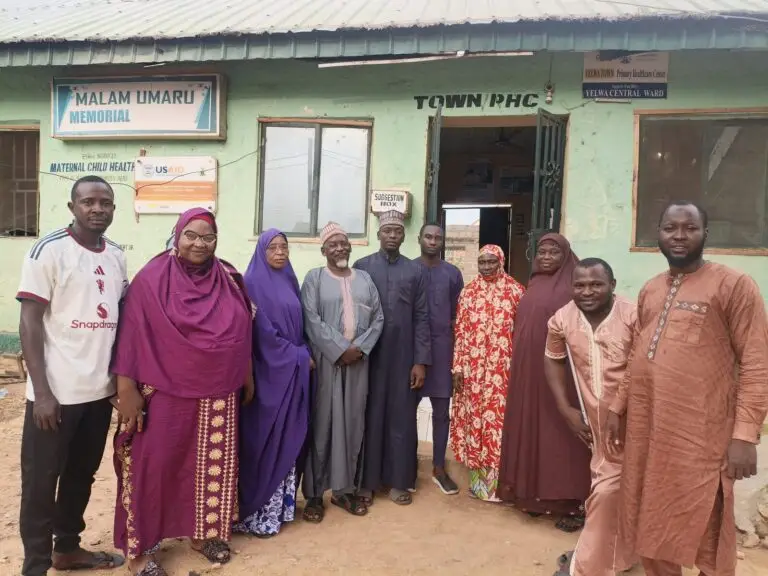 LHAAT members and health workers standing in front of Malam Umaru Memorial Town Primary Health Centre, Yauri, Kebbi