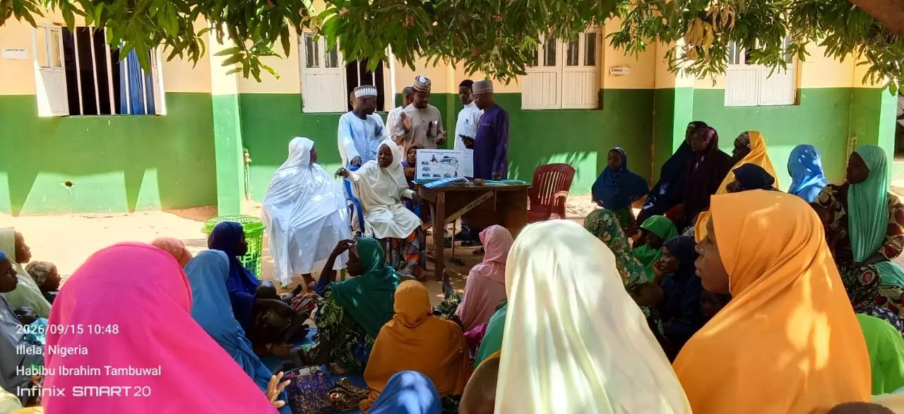 Community members seated under a tree during an outreach session at a primary health centre in Tambuwal, Sokoto